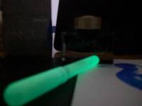 Glow in the dark A 3d printed pen, glowing in the dark rests before a bottle of gold lapis ink.